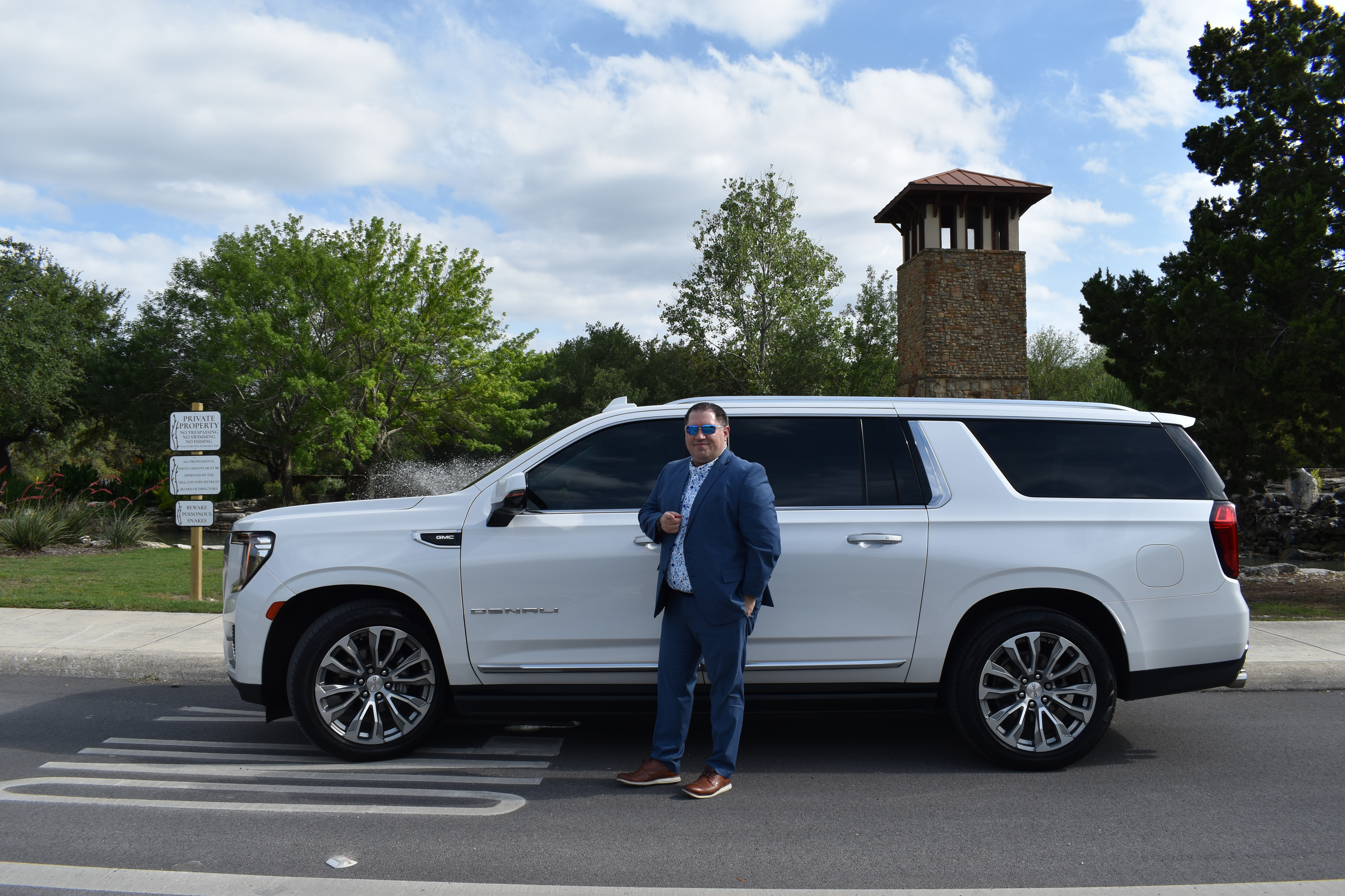 Anthony Baeza, founder of Outrider Executive Services, standing in front of his white GMC Yukon XL Denali